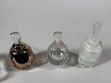 three glass perfume bottles sitting next to each other on a white surface