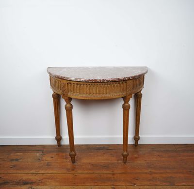 an old wooden table with a marble top on a hard wood floor