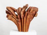 sculptures made of wood sit on a white pedestal against a white background