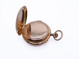 a gold pocket watch on a white surface