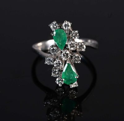 a close up of a diamond and emerald ring on a black surface