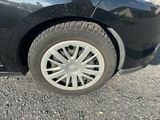 une voiture noire aux jantes blanches garée sur le bord de la route
