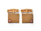 a pair of brown cufflinks with pink stones on them
