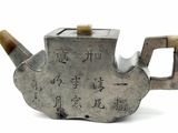 a silver teapot with writing on it on a white surface
