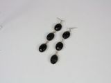 a pair of black glass earrings on a white surface