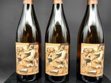 trois bouteilles de vin posées sur un bloc de marbre noir