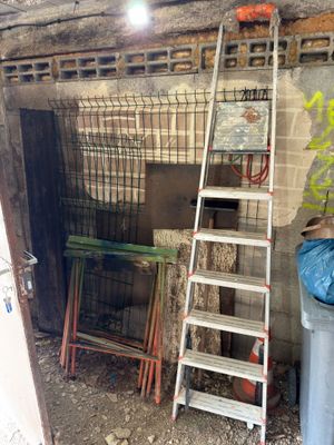 a ladder leaning up against a brick wall next to a trash can