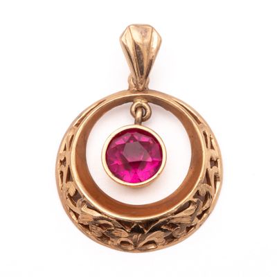 un gros plan d'un pendentif en or orné d'une pierre rose