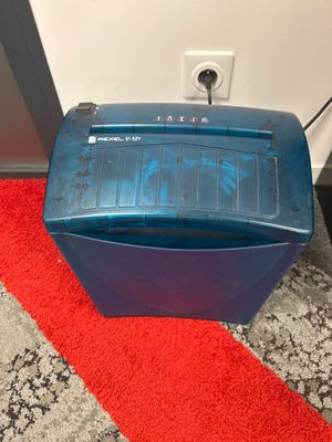 une déchiqueteuse bleue posée sur un tapis rouge