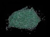 close up of a pile of green glitter on a black background