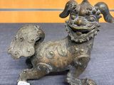 bronze statue of a dog on a blue surface with a tag