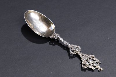 une cuillère en argent ancienne posée sur une surface noire, avec un fond noir