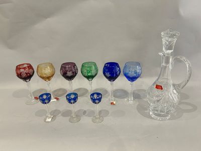 a lot of different colored wine glasses and a decanter on the table
