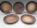 quatre assiettes marron empilées les unes sur les autres sur une surface blanche