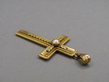 un gros plan d'une croix en or ornée d'une perle
