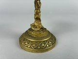 brass figurine of a person holding a cross on a pedestal