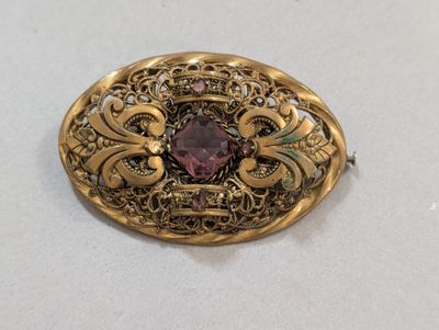 une broche ancienne en or ornée d'une pierre rose entourée de filigranes