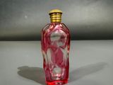 une bouteille en verre rouge avec un bouchon doré posée sur une table