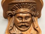 un gros plan sur une plaque en bois sur laquelle est représenté un visage