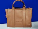 a brown leather handbag on a table with a blue background