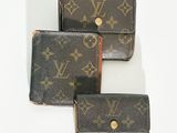 trois portefeuilles Louis Vuitton posés sur une surface blanche