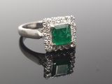 an emerald and diamond ring on a reflective surface