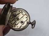 a person holding a silver pocket watch in their hand