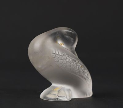 a glass bird that is sitting on a black surface