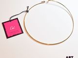 une photo d'un collier en or auquel est accrochée une étiquette rose
