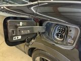 a black car with an electric charger attached to it ' s side