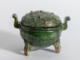 un petit pot vert muni d'un couvercle, posé sur un socle
