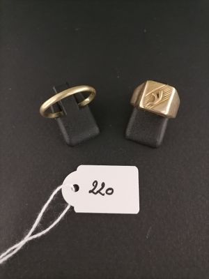 two gold and black cuff rings with a price tag on a black surface
