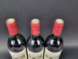 three bottles of red wine sitting on top of a black table