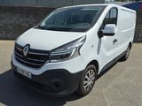 La camionnette blanche est garée sur le parking, à côté d'un mur de briques.
