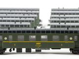 two green train cars sitting next to each other on the tracks