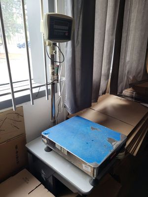 une balance posée sur une table dans une pièce où se trouvent des cartons