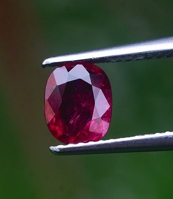 un gros plan d'un diamant rouge tenu par une pince