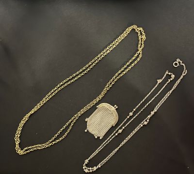 deux chaînes en or et un sac à main posés sur une surface noire