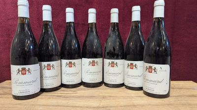 six bottles of wine are lined up on a wooden table