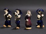 three figurines of people dressed in different outfits and hats