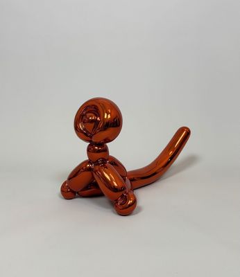 a shiny orange cat statue sitting on a white surface