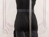 a black dress on a mannequin stand in front of a white wall