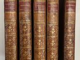 cinq vieux livres sont alignés les uns à côté des autres sur une étagère