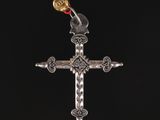 une croix en argent à laquelle est suspendu un ruban rouge