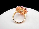 an image of a gold ring with pink stones on top of a white surface