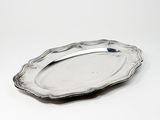 une assiette en argent posée sur une surface blanche, avec une cuillère dessus