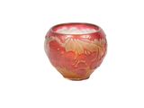 un vase rouge et doré posé sur une surface blanche