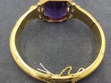 a close up of a gold ring with a purple stone on it