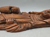 an old wooden statue of a person laying on a bed
