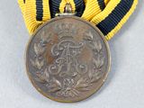 an old medal with a ribbon around it and a crown on top of it